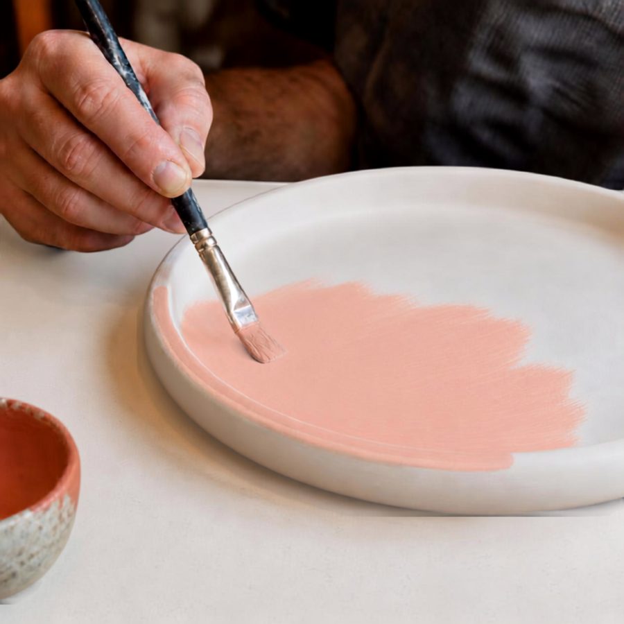 Hand painting the rim of a ceramic plate