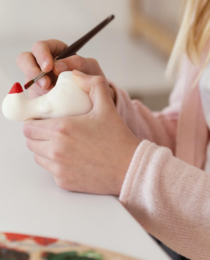 Hands painting a ceramic pottery piece